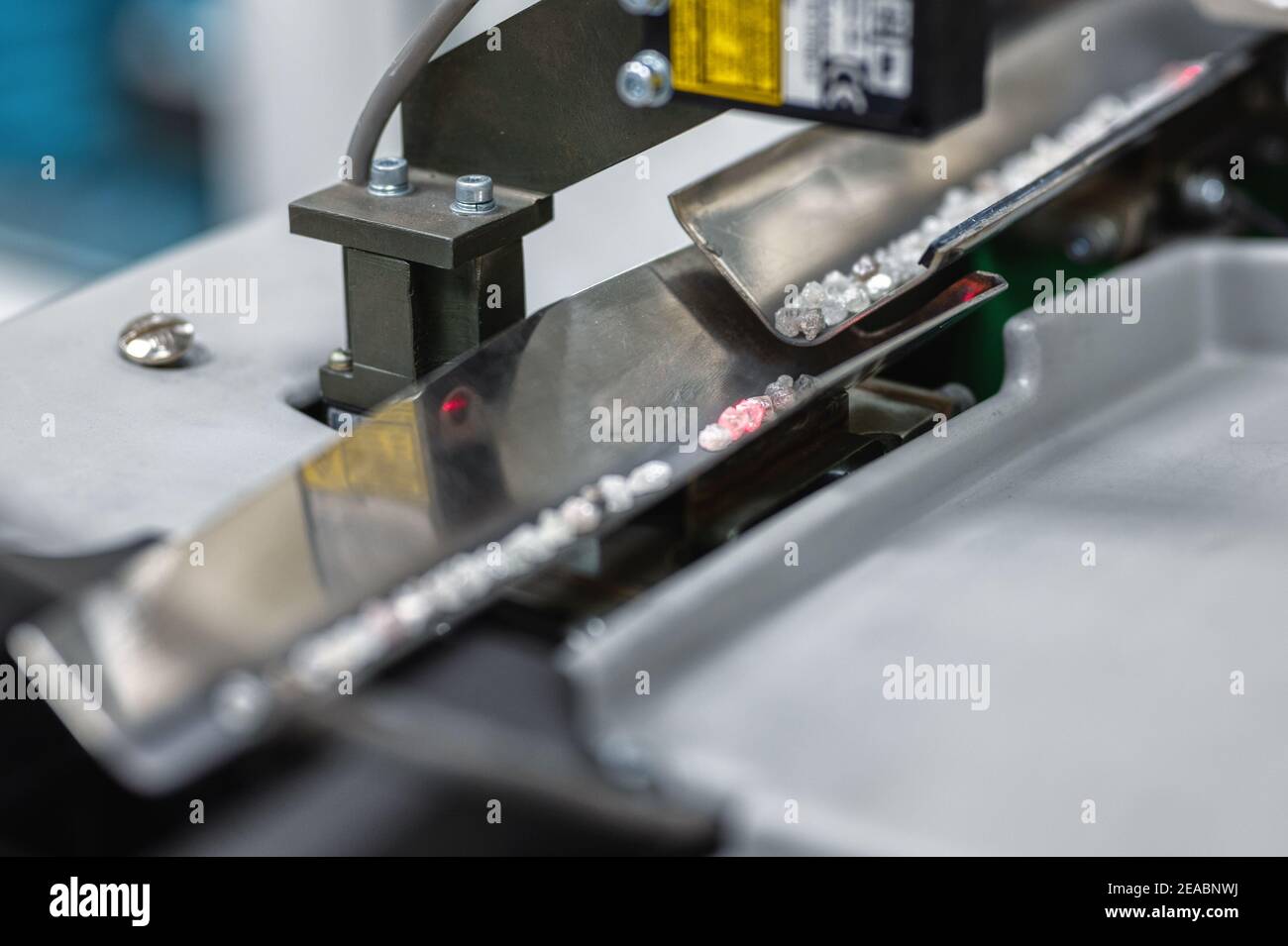 Smistamento automatico dei diamanti, moderne tecnologie di visione artificiale. I diamanti si muovono lungo un vassoio angolare in metallo Foto Stock