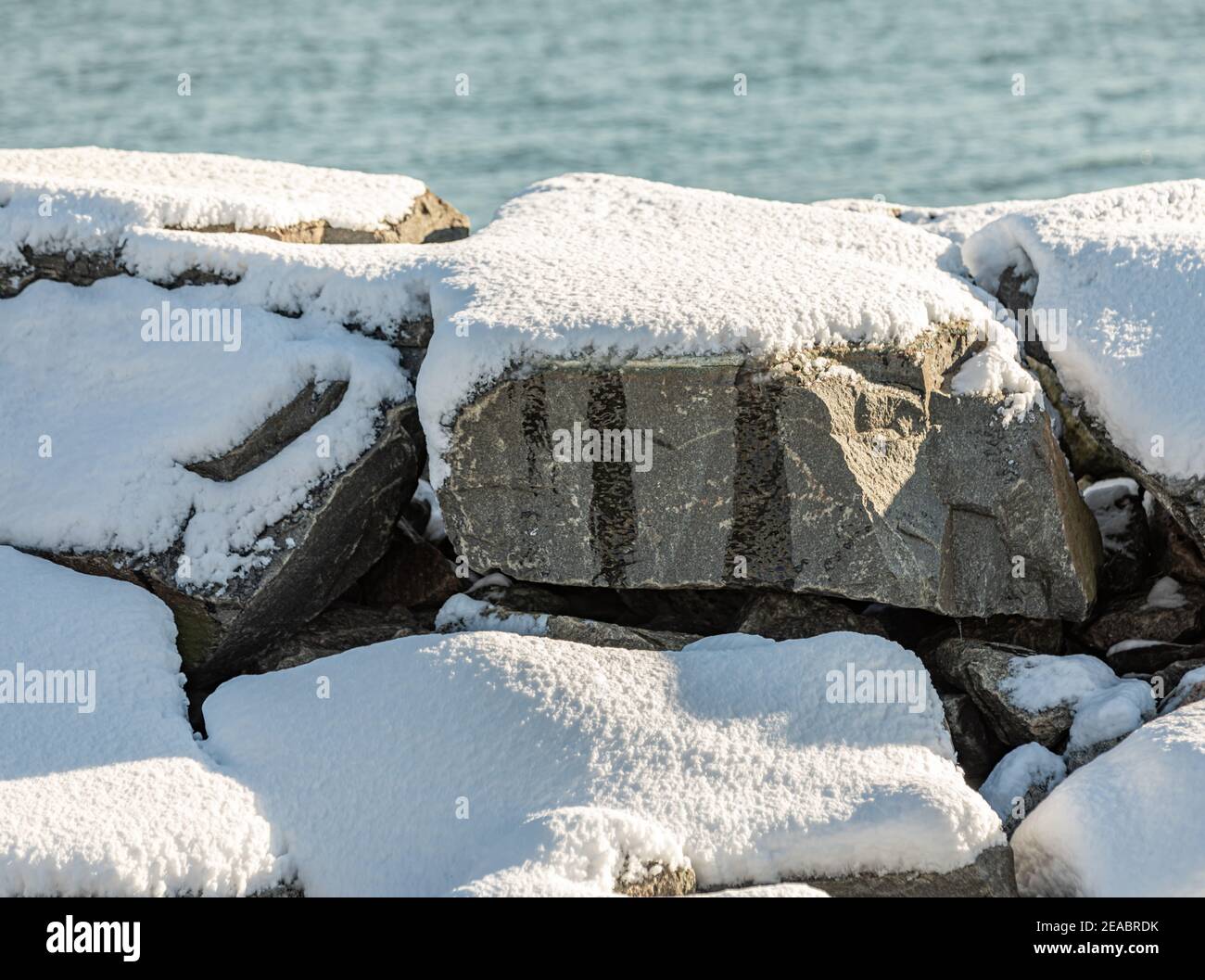 grandi massi coperti di neve dall'acqua Foto Stock
