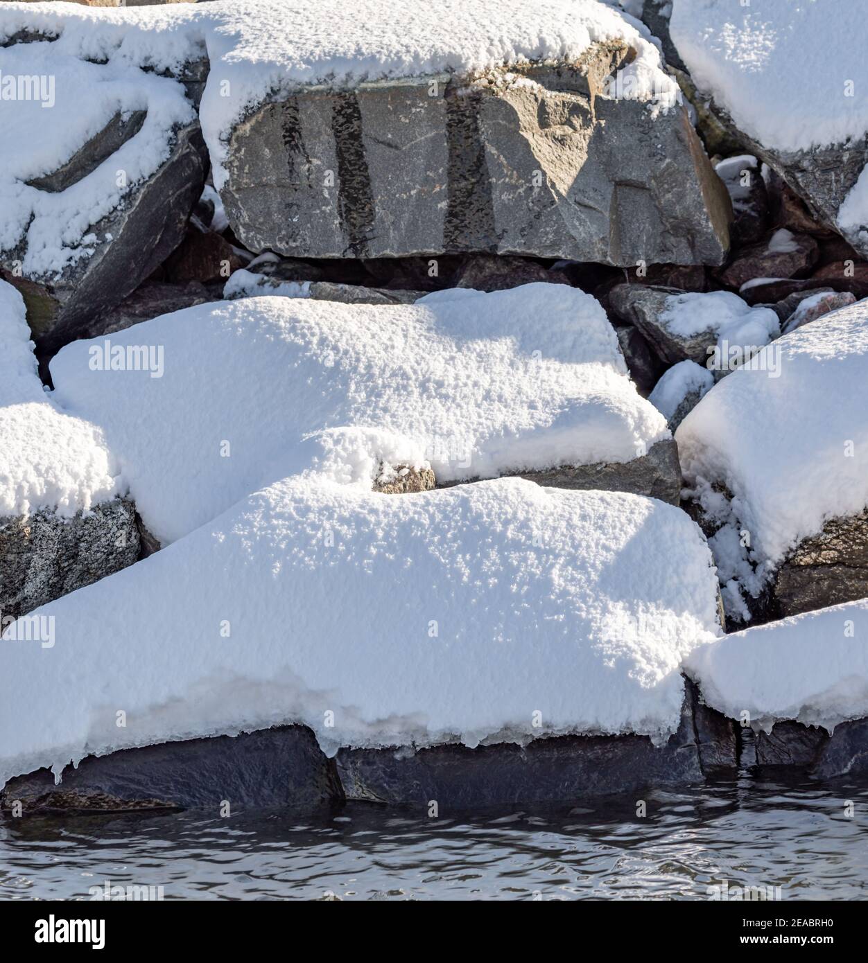grandi massi coperti di neve dall'acqua Foto Stock