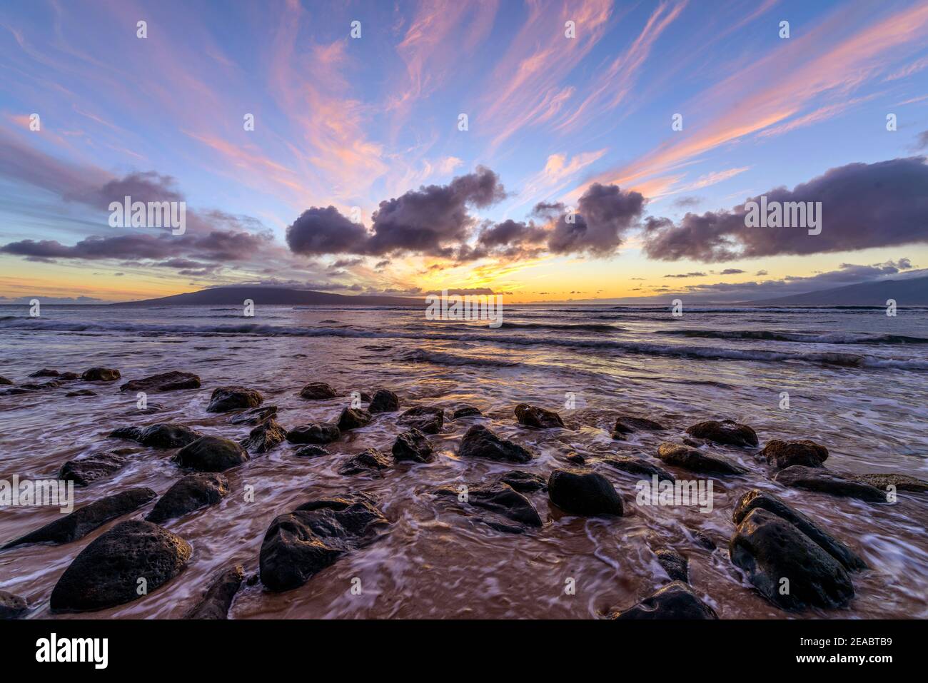 Sunset Rocky Coast - una colorata vista del tramonto su una costa rocciosa della costa nord-occidentale dell'isola di Maui, con l'isola di Lanai all'orizzonte. Maui, Hawaii, Stati Uniti. Foto Stock