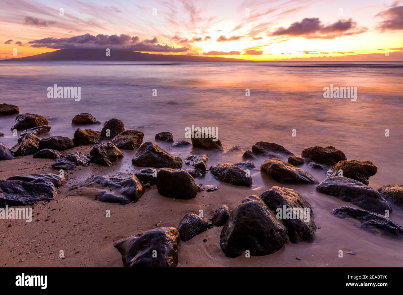 Sunset Island - una vista a lunga esposizione di un colorato tramonto su una spiaggia rocciosa della costa nord-occidentale dell'isola di Maui, Hawaii, USA. Foto Stock