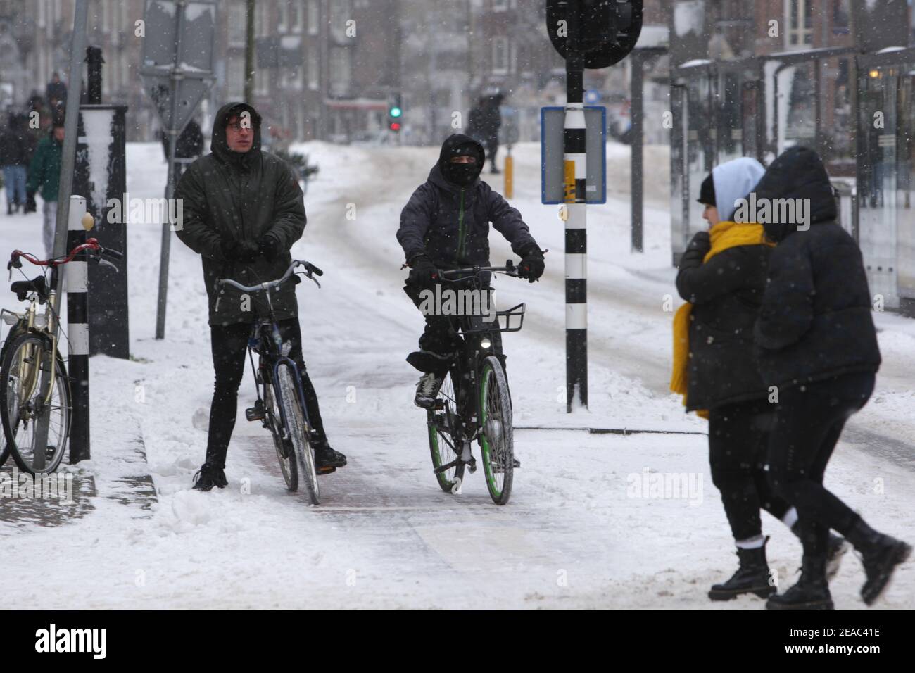 I membri del pubblico camminano e fanno un giro in bicicletta attraverso la neve sulla strada il 7 febbraio 2021 ad Amsterdam, Olanda. L'ufficio meteo olandese è Foto Stock
