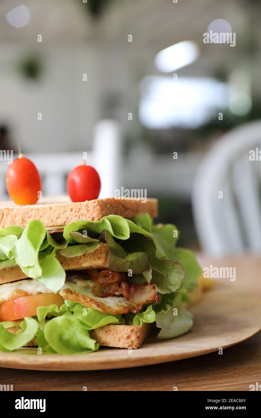 Club sandwich con prosciutto, pancetta, pomodoro, formaggio, uova e fritto su sfondo di legno Foto Stock