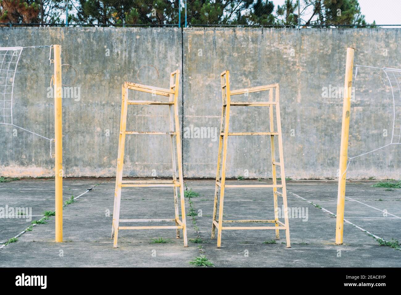 Gialle, metallo, vintage linea giudicate sedie a vecchio cemento campo da pallavolo all'aperto. Foto Stock