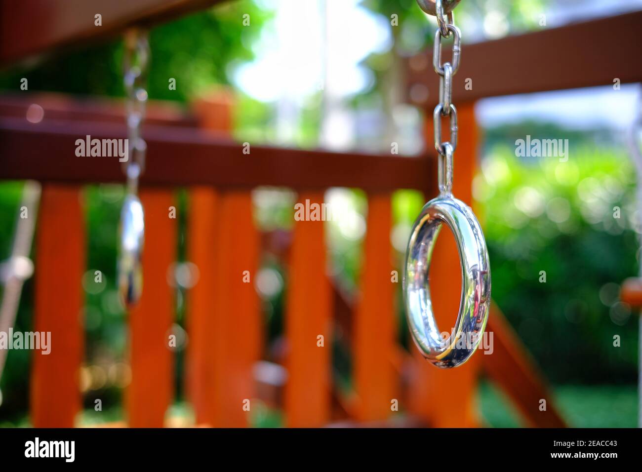 Un'immagine ravvicinata di un parco giochi pubblico con anelli per ginnastica in acciaio, ponte in legno e scale. Foto Stock