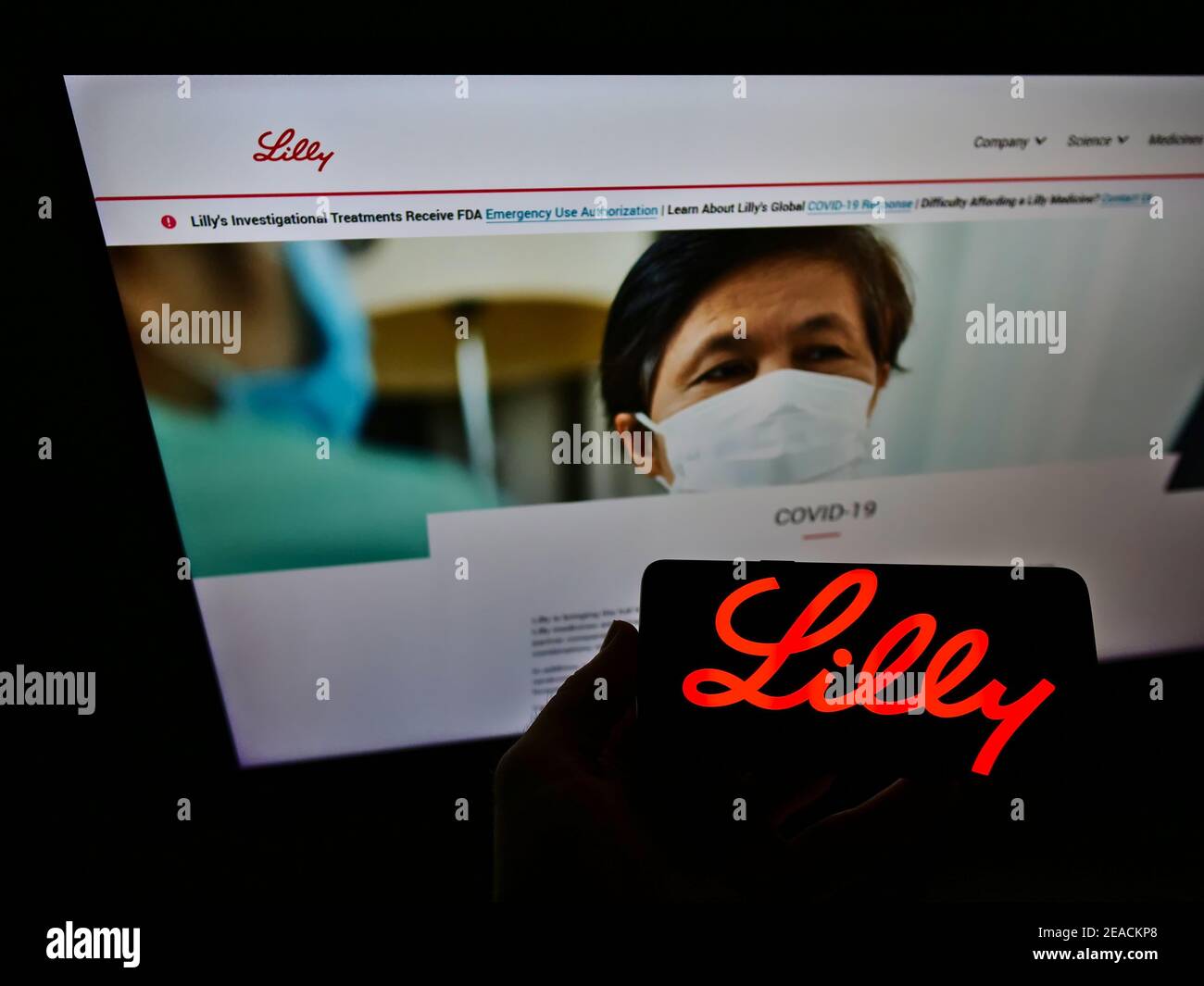 Persona che tiene il cellulare con il logo commerciale della società farmaceutica statunitense Eli Lilly e Company sullo schermo di fronte al sito web. Mettere a fuoco il display del telefono. Foto Stock