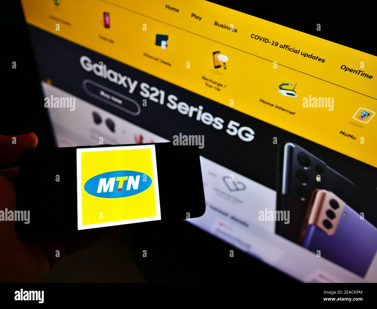 Persona che tiene il cellulare con il logo della società di telecomunicazioni sudafricana MTN Group sullo schermo davanti alla pagina web. Mettere a fuoco il display del telefono. Foto Stock
