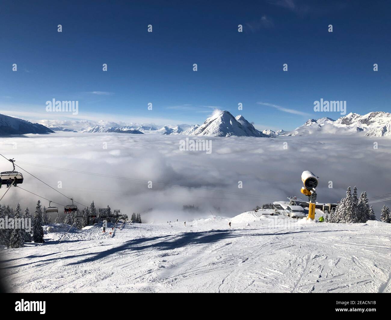 Area sciistica Rosshütte, cannone da neve, seggiovia Rosshütten-Express, mare di nebbia, sole, montagne, Alpi, Hohe Munde, Seefeld in Tirol, Austria Foto Stock