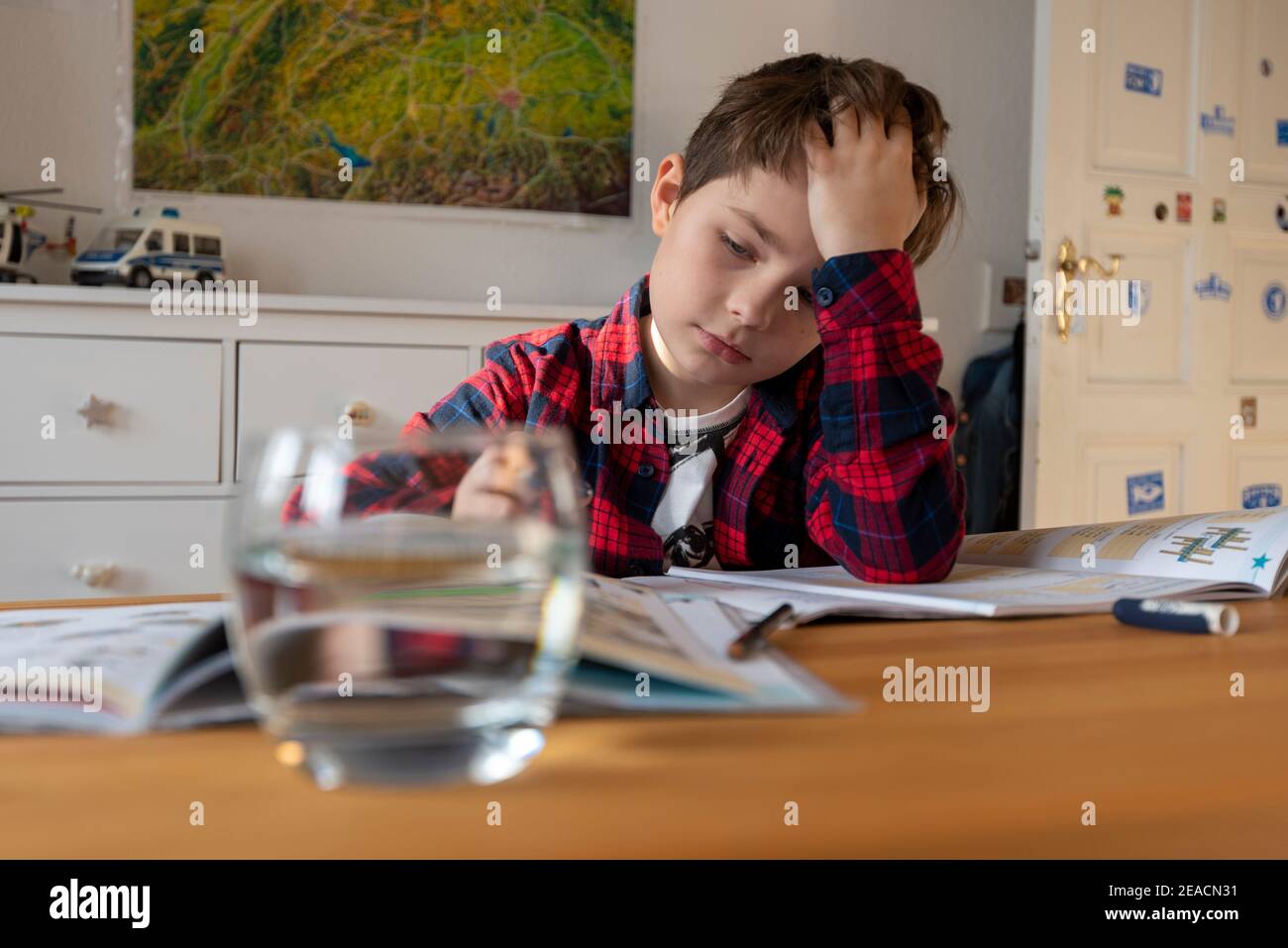 Un ragazzo si siede alla sua scrivania in homeschooling facendo i chores per la scuola. Foto Stock