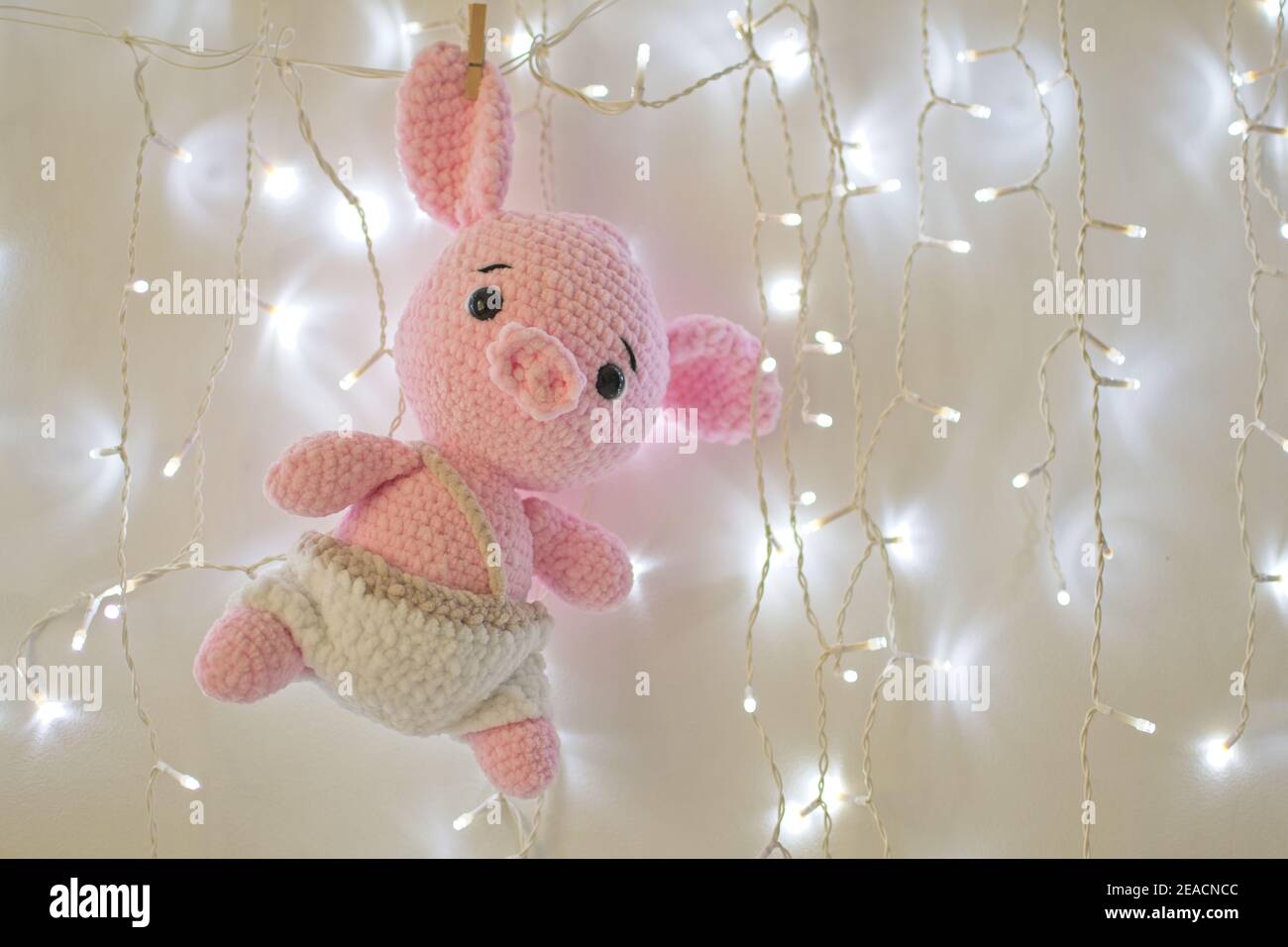 Morbido maiale giocattolo appeso tra luci stringa Foto Stock