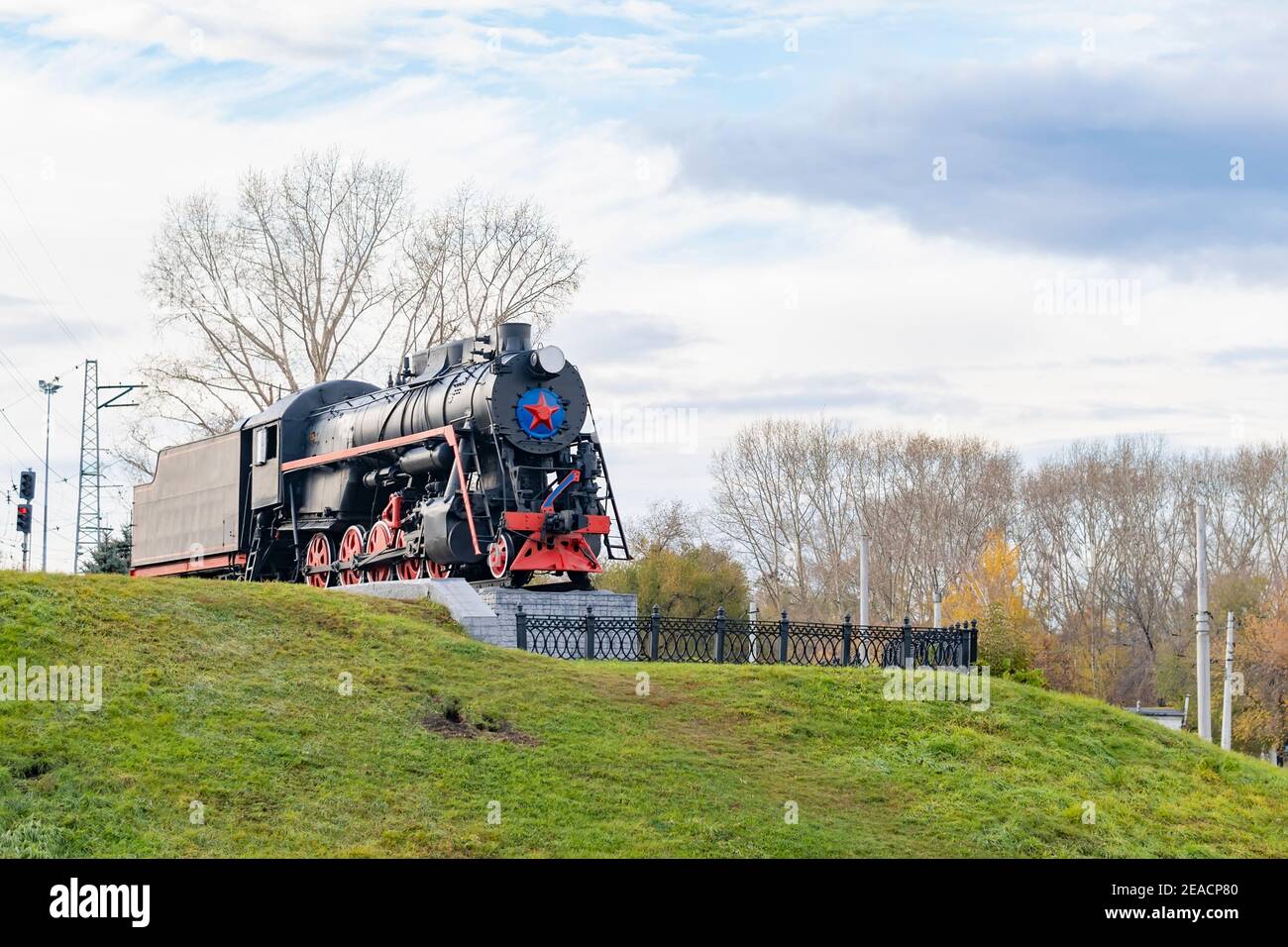 Vecchio treno d'epoca sovietico, locomotiva a vapore con una stella rossa si erge su un piedistallo come monumento, un punto di riferimento della città Foto Stock