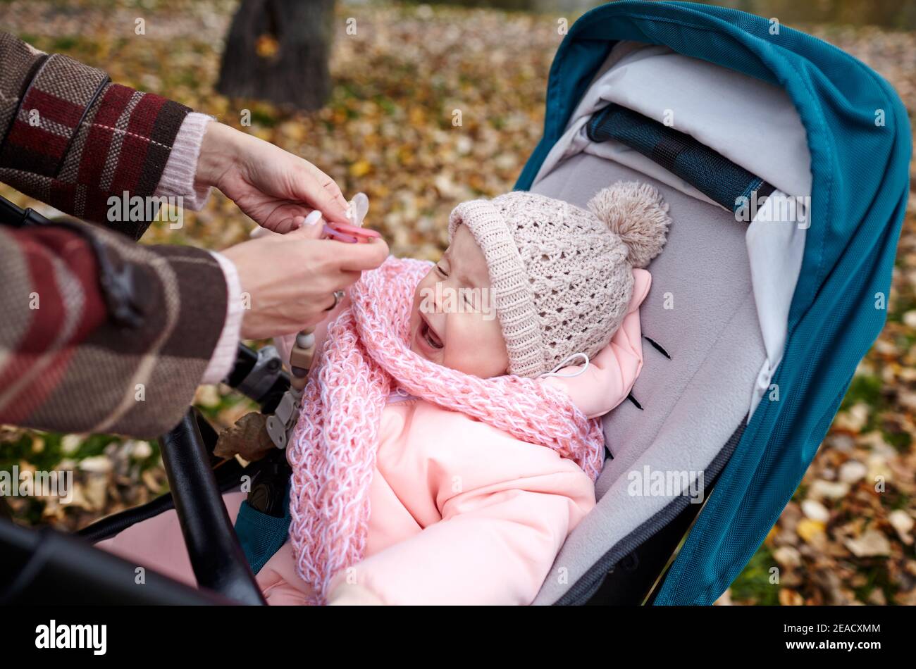 Il bambino piange. Baby in passeggino in una passeggiata nel parco  autunnale. Adorabile bambina in abiti caldi seduta in carrozzina blu Foto  stock - Alamy