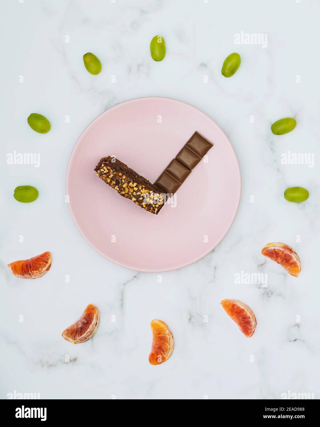 Rappresentazione di un orologio fatto con cioccolato e pezzi di frutta fresca Foto Stock