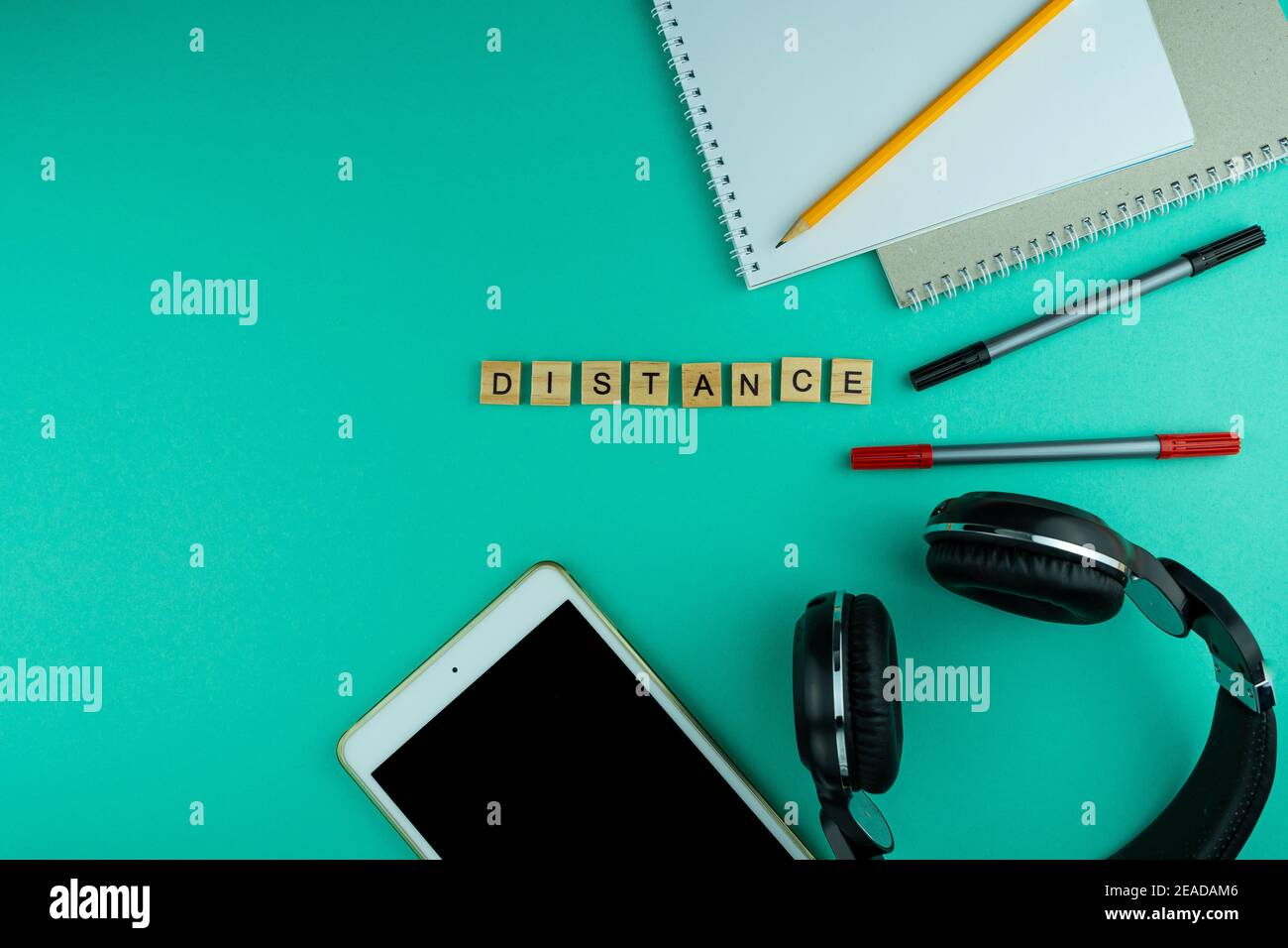 Distanza. La frase è scritta in lettere di legno. Vista dall'alto. Motivazione. Spazio di copia. Tablet, cancelleria per cuffie. Apprendimento a distanza. Tabella F Foto Stock