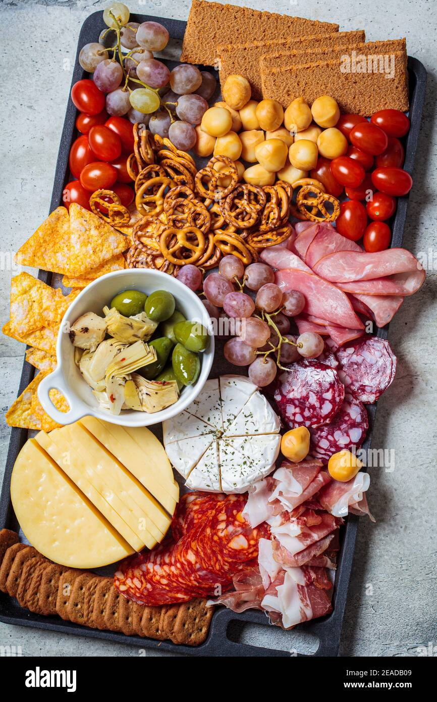 Piatto di salumi e formaggi. Vassoio di antipasti con carni assortite,  formaggi, frutta, olive e cracker Foto stock - Alamy