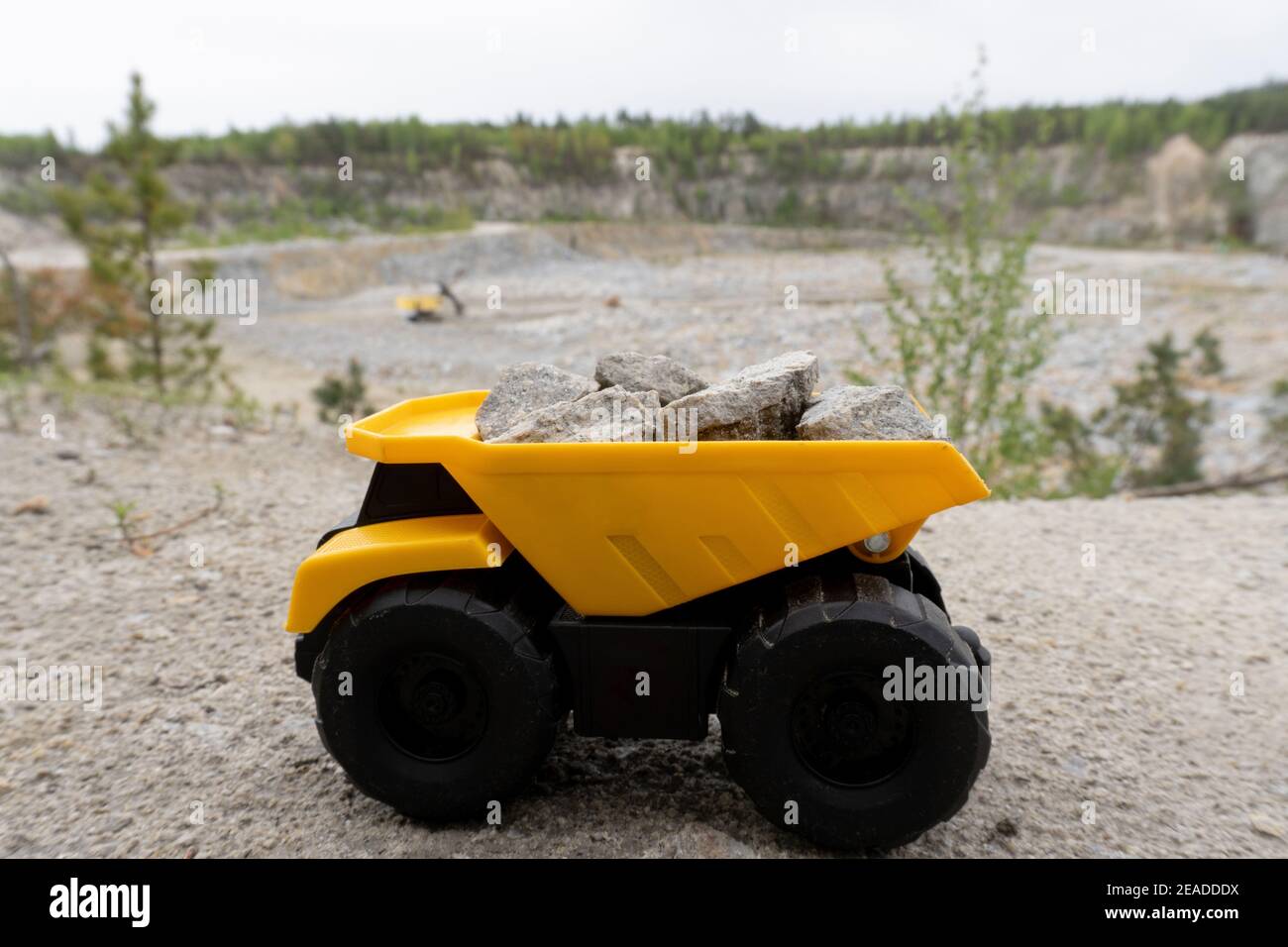 Piccolo giocattolo giallo per auto, camion minerario con pietre. Foto Stock