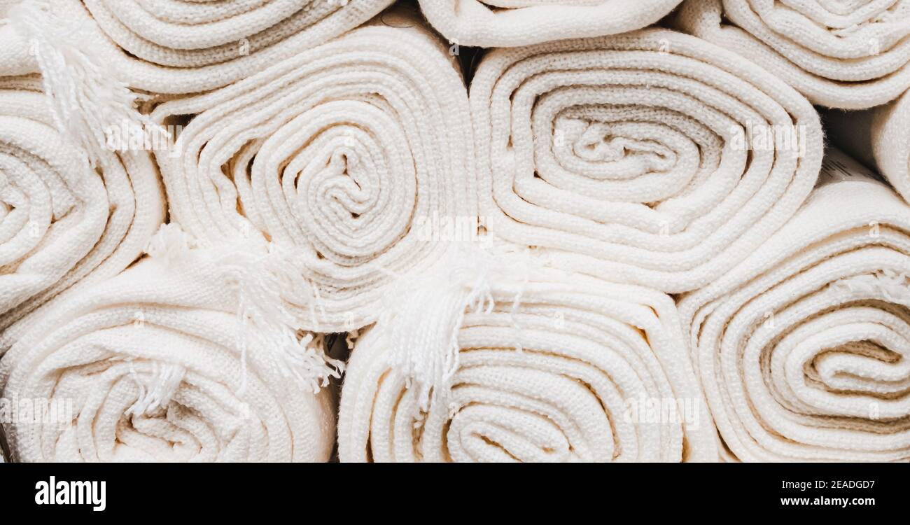 Primo piano su molti rotoli di tappeti bianchi impilabili. Foto Stock