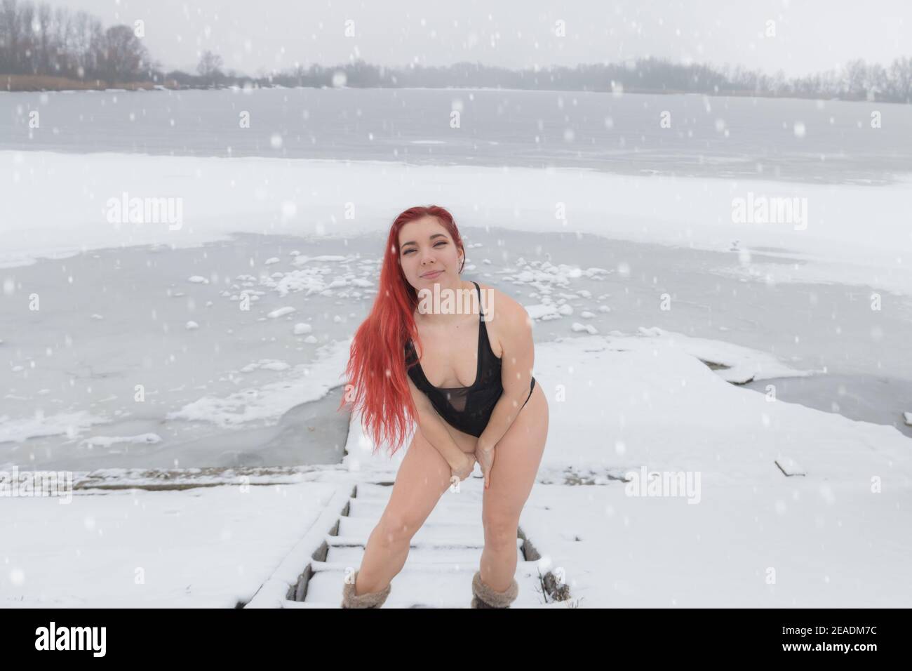 Splendida donna in costume da bagno sulla neve al lago gelido inverno acqua fredda corpo indurente Foto Stock