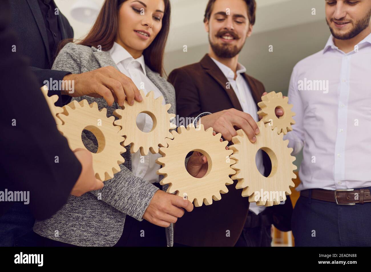 Lavoratori aziendali che si uniscono a ruote dentate come metafora per un sistema aziendale efficiente e gestione Foto Stock