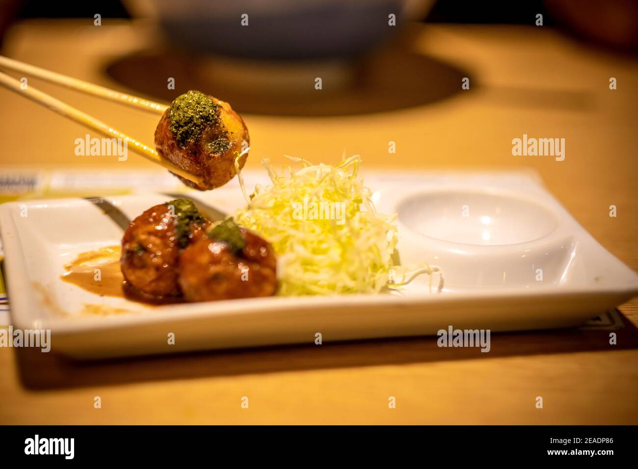 Closeup di takoyaki, Chopstick bloccato takoyaki palla, legno sfondo tavolo. Foto Stock