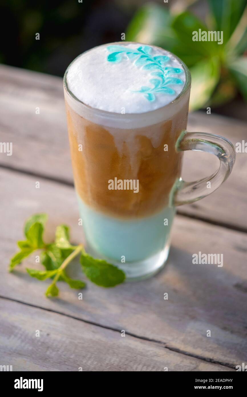 Menta con caffè ghiacciato in vetro con foglie di menta su sfondo di tavola di legno. Foto Stock