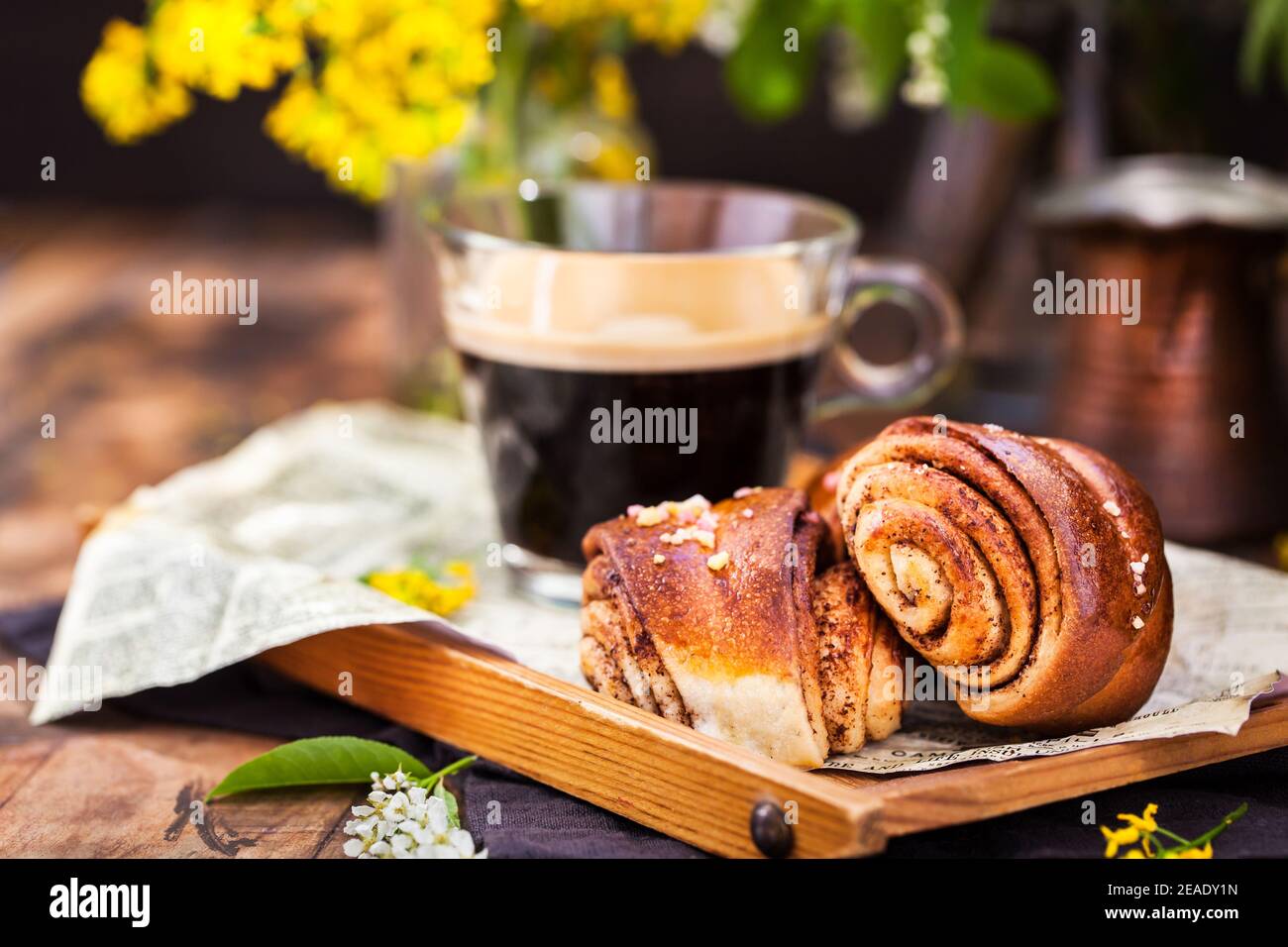 Dolci fatti in casa alla cannella e cardamomo (panini) e una tazza di caffè nero Foto Stock