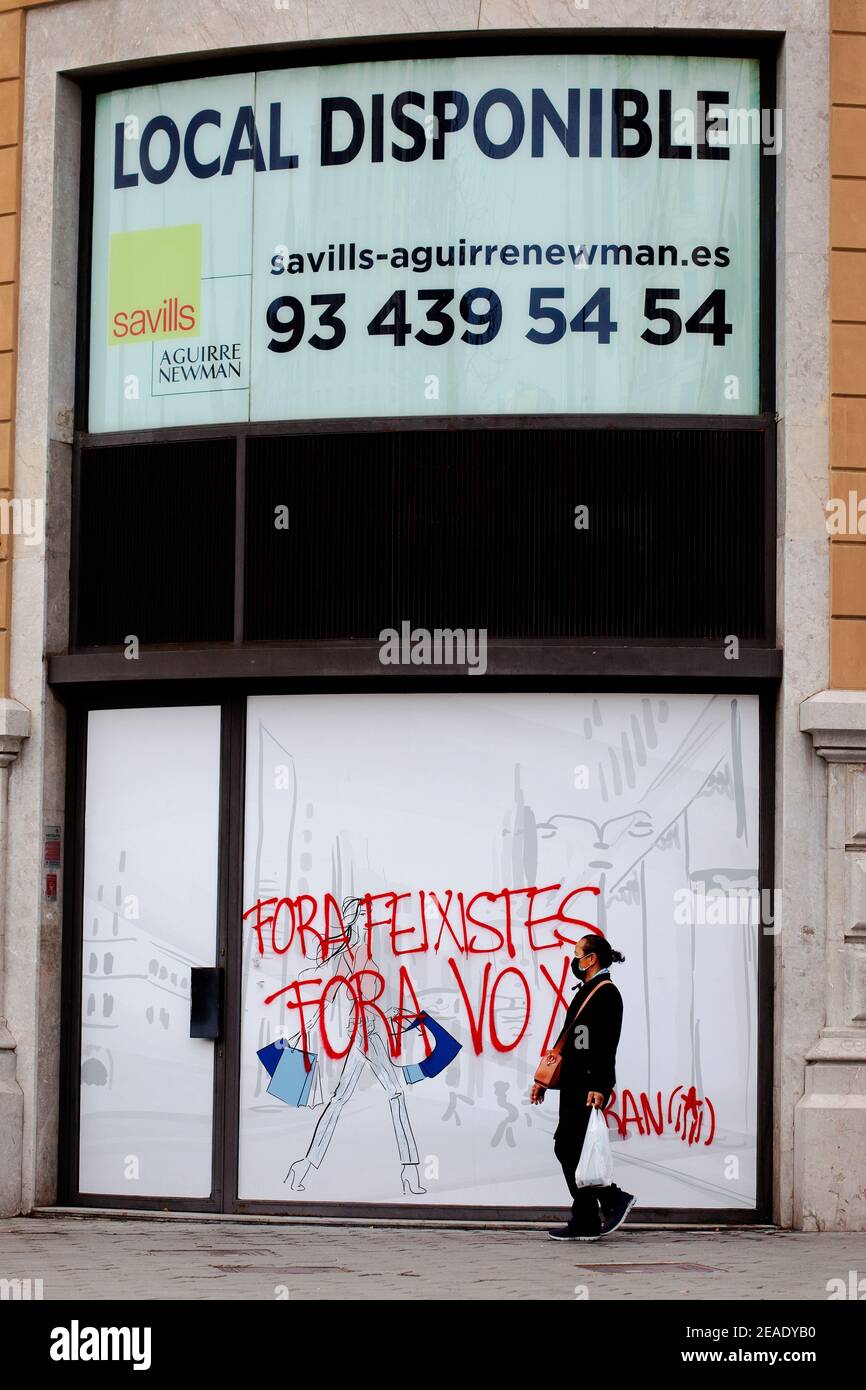 L'uomo asiatico passa davanti a locali vuoti spruzzati di graffiti antifascisti, Barcellona, Spagna. Foto Stock