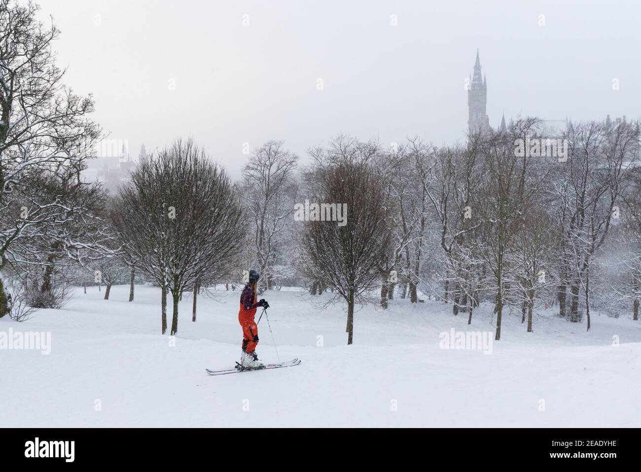 Le persone che si godono la neve invernale a Kelvingrove Park Glasgow UK. Bambini su slitta. Sciare nel parco. Ciclista. Tempesta invernale. Università di Glasgow. Foto Stock