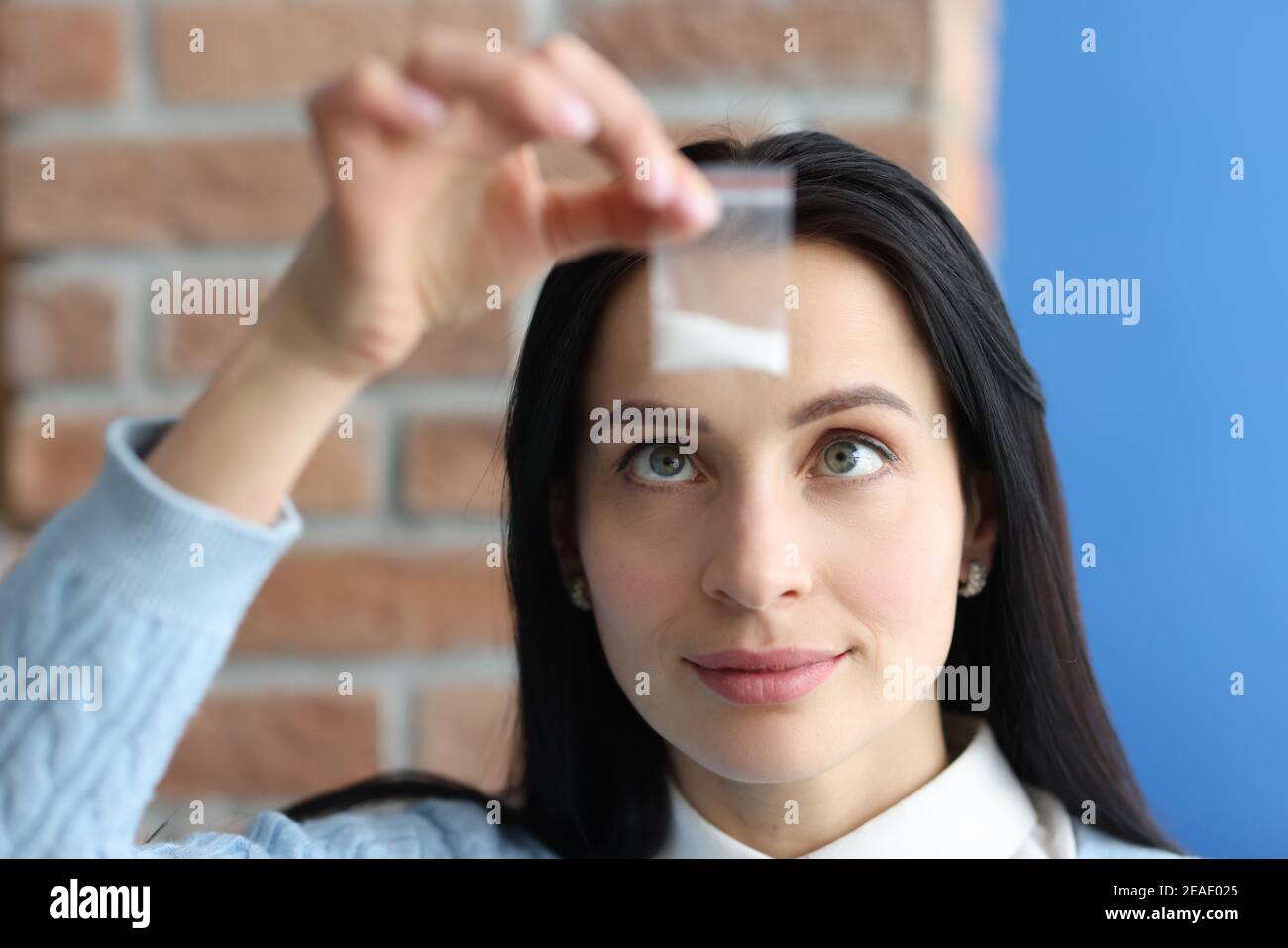 La donna sta tenendo una piccola confezione di polvere bianca Foto Stock