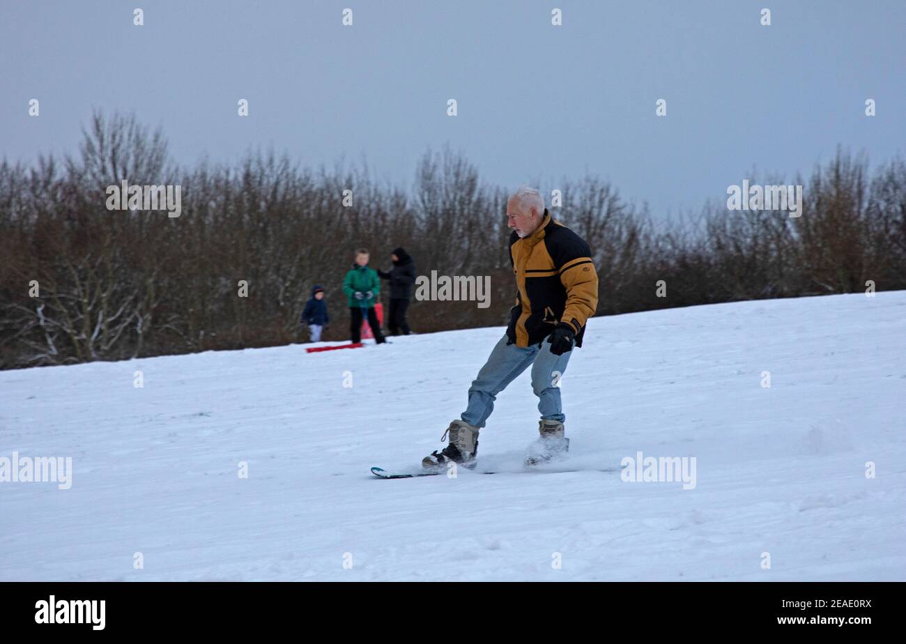 Holyrood Park Edimburgo, Scozia, Regno Unito. 9 febbraio 2021. Il Parco Holyrood innevato ha incoraggiato le persone a giocare e ad allenarsi tra le docce. Più vecchio snowboarder godendo di una corsa lungo la pendenza. Foto Stock