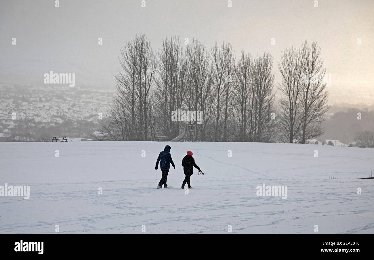 Holyrood Park Edimburgo, Scozia, Regno Unito. 9 febbraio 2021. Il Parco Holyrood innevato ha incoraggiato le persone a giocare e ad allenarsi tra le docce. Coppia che cammina in una doccia di neve pesante. Foto Stock