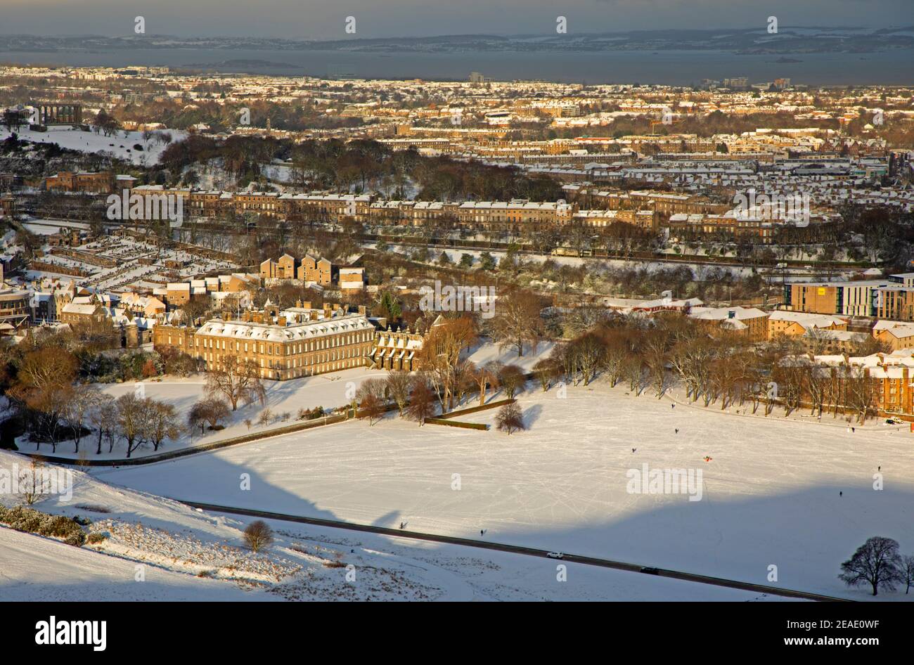Holyrood Park Edimburgo, Scozia, Regno Unito. 9 febbraio 2021. Il Parco Holyrood innevato ha incoraggiato le persone a giocare e ad allenarsi tra le docce. Il Palazzo Holyrood e gli edifici circostanti catturano la luce del sole del mattino presto mentre brilla sulla collina. Foto Stock