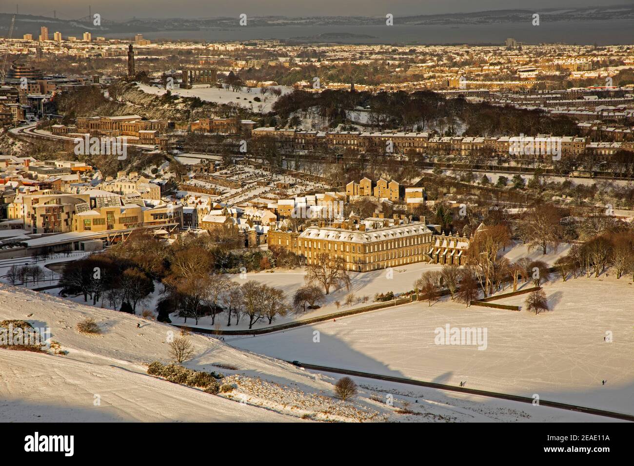 Holyrood Park Edimburgo, Scozia, Regno Unito. 9 febbraio 2021. Il Parco Holyrood innevato ha incoraggiato le persone a giocare e ad allenarsi tra le docce. Il Palazzo Holyrood e gli edifici circostanti catturano la luce del sole del mattino presto mentre brilla sulla collina. Foto Stock