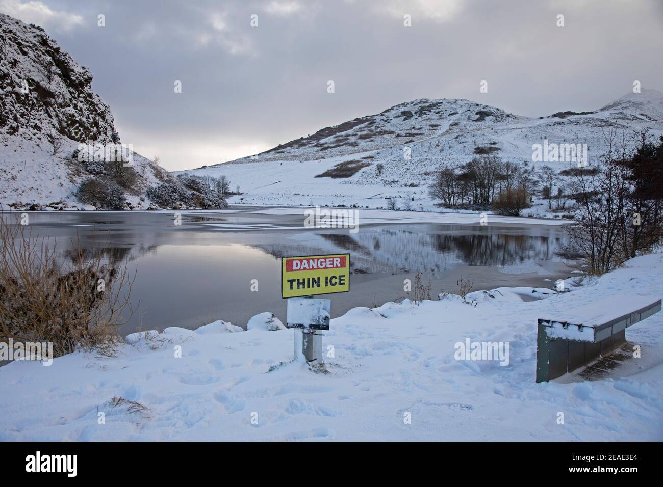 Holyrood Park Edimburgo, Scozia, Regno Unito. 9 febbraio 2021. Il Parco Holyrood innevato ha incoraggiato le persone a giocare e ad allenarsi tra le docce. Nella foto:segnale di avvertimento del ghiaccio sottile sul lago. Foto Stock