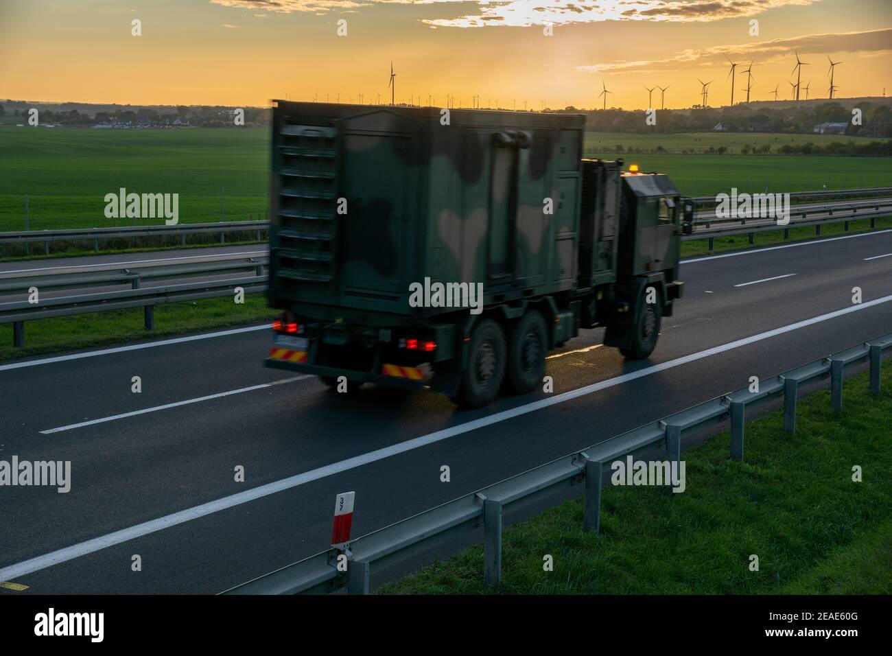 Veicolo militare che guida in autostrada al tramonto Foto Stock