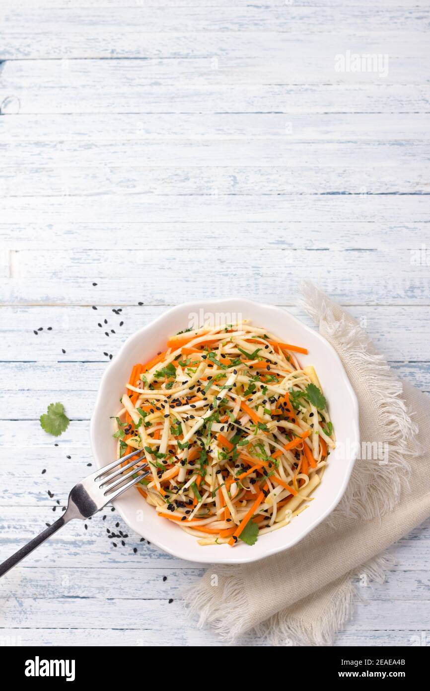 Insalata di sedano con carote, mele, coriandolo, sesamo e spezie su sfondo blu, vista dall'alto, spazio libero. Deliziosi cibi sani fatti in casa Foto Stock