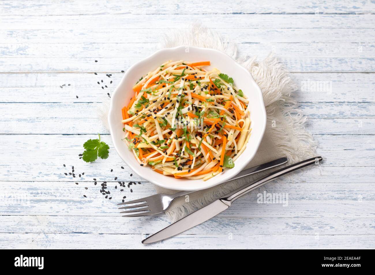 Insalata di sedano con carote, mele, coriandolo, sesamo e spezie su sfondo blu, vista dall'alto, spazio libero. Deliziosi cibi sani fatti in casa Foto Stock