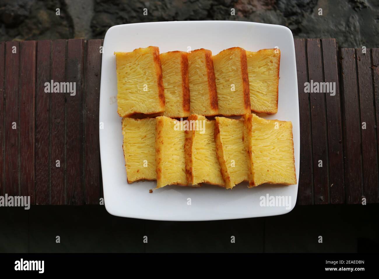 Bika Ambon, torta indonesiana a fette quadrate in piatto bianco. Torta gialla di Medan, Indonesia. Foto Stock