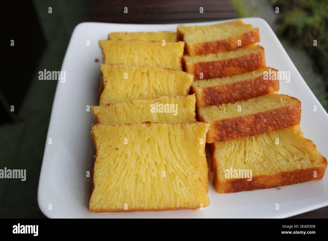 Bika Ambon, torta indonesiana a fette quadrate in piatto bianco. Torta gialla di Medan, Indonesia. Foto Stock