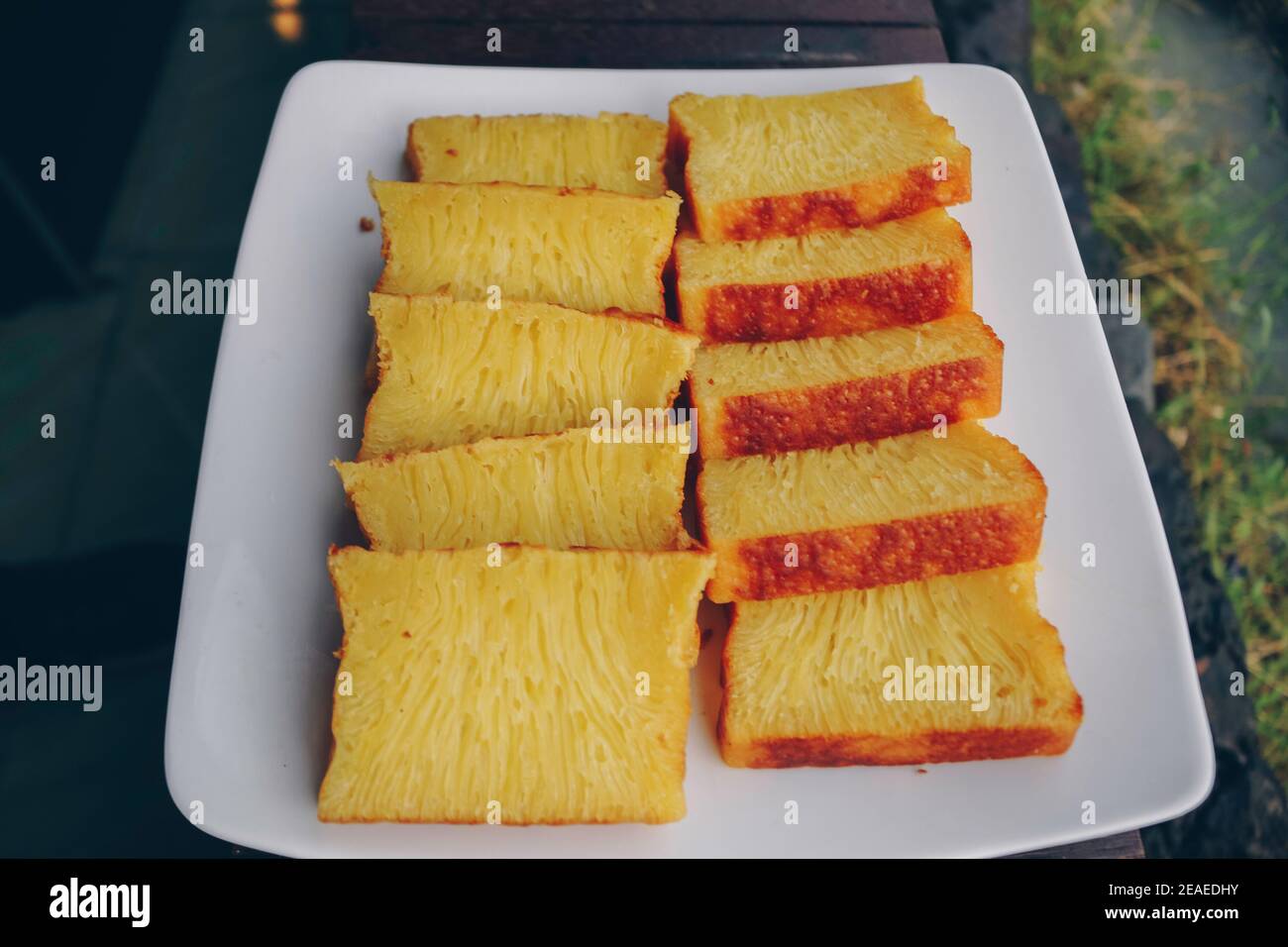 Bika Ambon, torta indonesiana a fette quadrate in piatto bianco. Torta gialla di Medan, Indonesia. Foto Stock