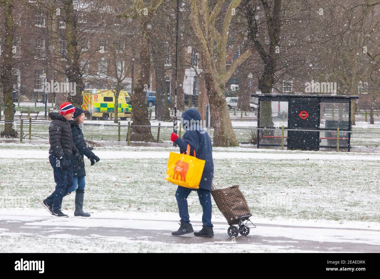 Londra, Regno Unito. 9 febbraio 2021: Dopo tre giorni di neve a Londra inizia a stabilirsi e i venti sono caduti mentre Storm Darcy è passato. Sul Clapham Common alcune persone prendono l'esercizio o tornano dai negozi e passa un'ambulanza. Credit: Anna Watson/Alamy Live News Foto Stock