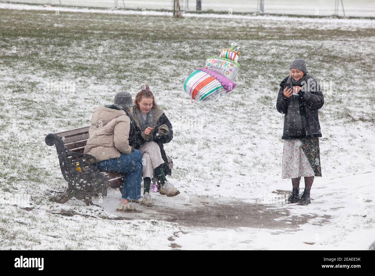 Londra, Regno Unito. 9 febbraio 2021: Dopo tre giorni di neve a Londra inizia a stabilirsi e i venti sono caduti mentre Storm Darcy è passato. Su Clapham Common tre giovani donne celebrano un compleanno che osserva le regole sociali di allontanamento Anna Watson/Alamy Live News Foto Stock