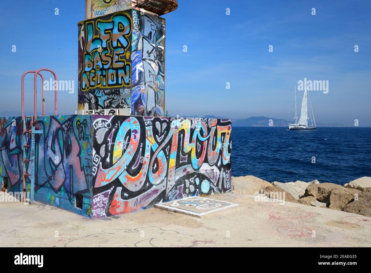 Graffiti o Street Art 'Espoir' o Hope on Lighthouse & Quayside con Barca a vela o Yacht off calcestruzzo Breakwater a. La Ciotat Provenza Francia Foto Stock