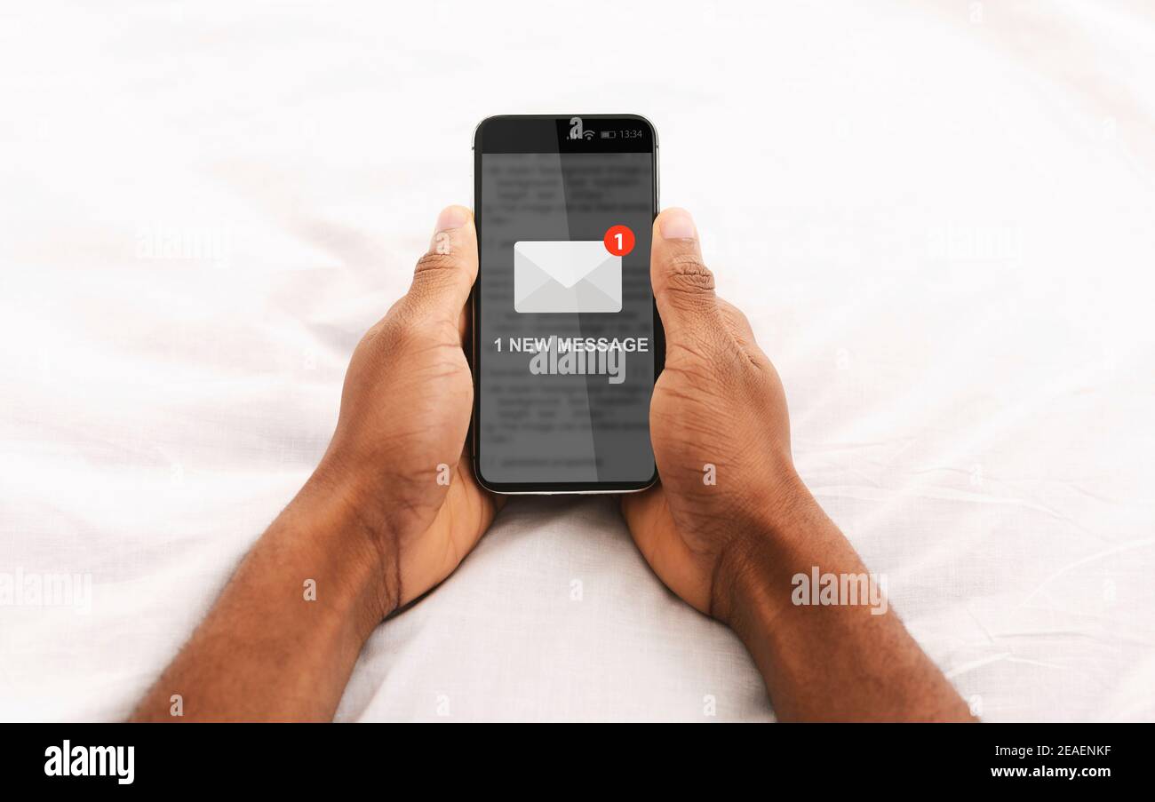 African Man Holding cellulare lettura e-mail lettera in linea in Camera da Letto Foto Stock