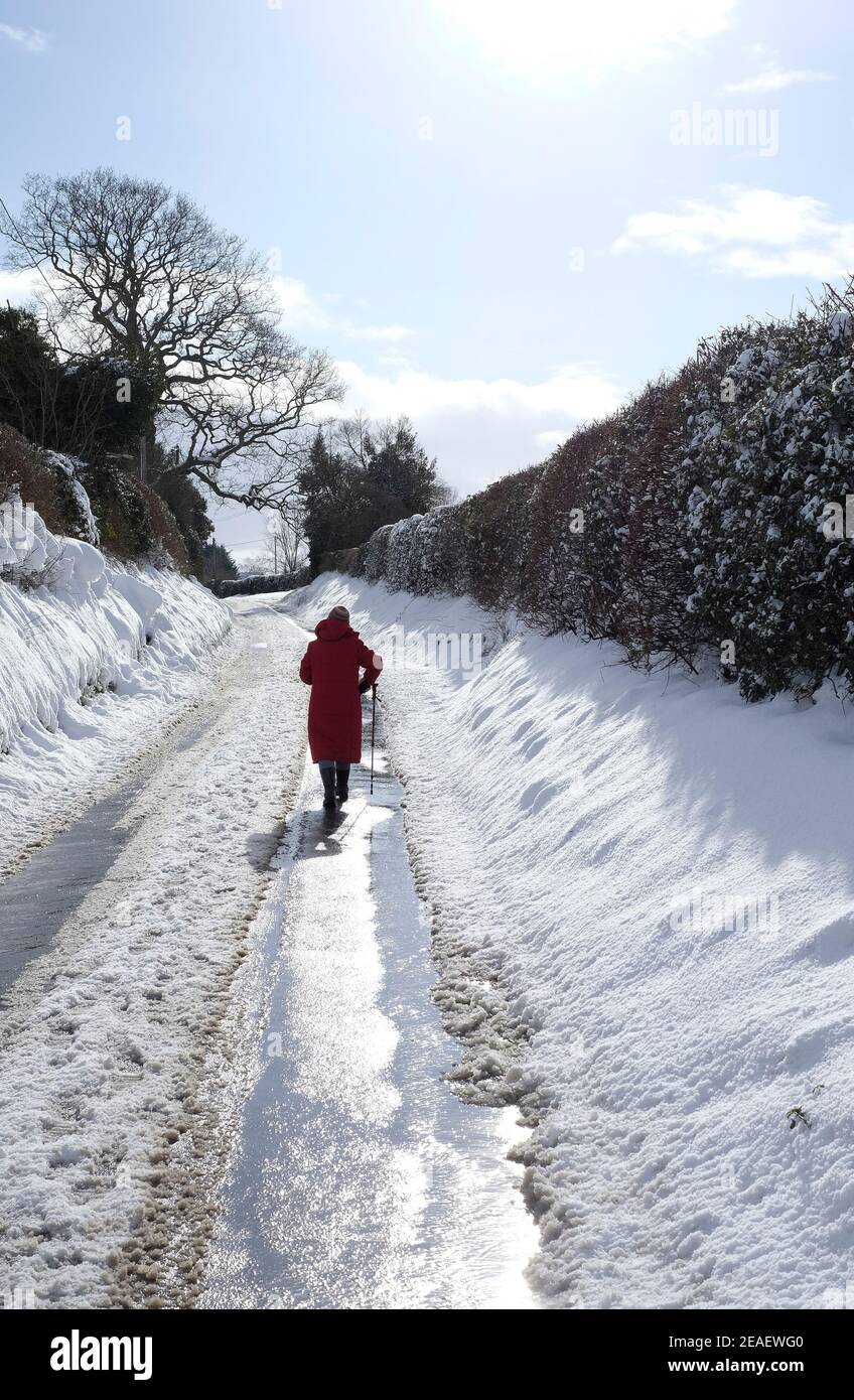 persona anziana che cammina sulla corsia di campagna innevata, costabile di melton, norfolk del nord, inghilterra Foto Stock