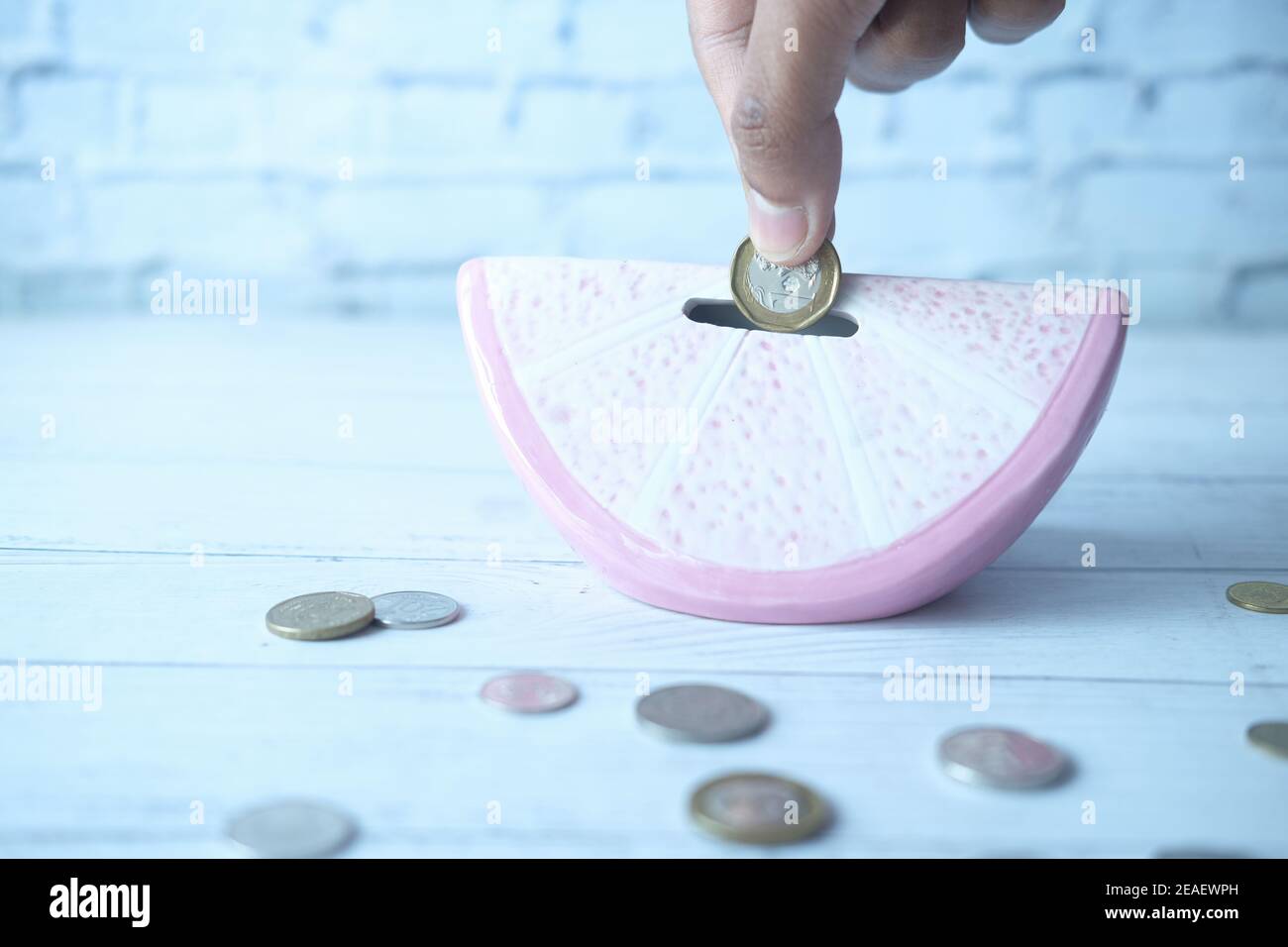 mano di una persona che salva le monete in una banca di moneta Foto Stock