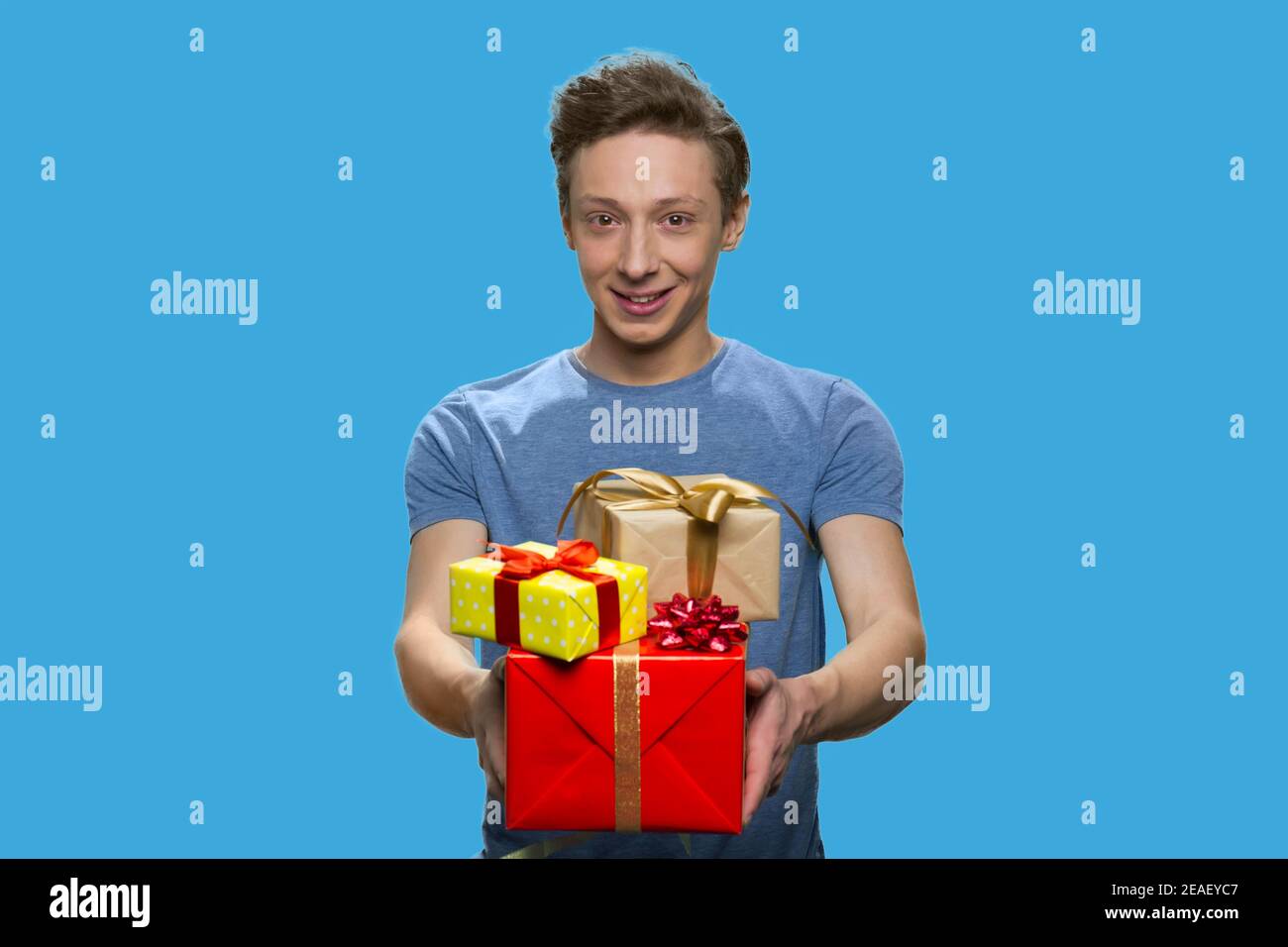 Ritratto del ragazzo sorridente in t-shirt contenente confezioni regalo. Foto Stock