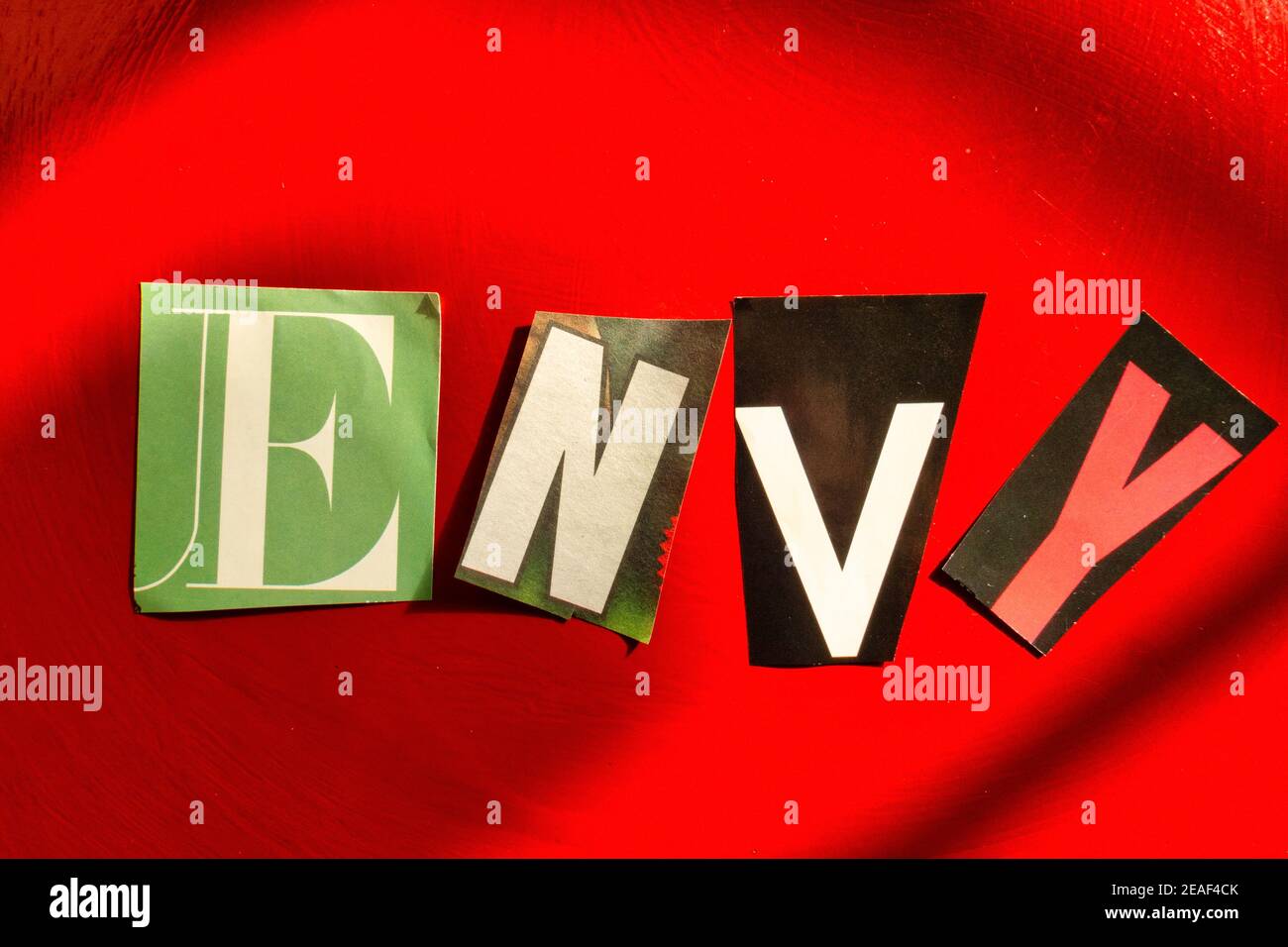 TheWord 'invy' usando le lettere di carta ritagliate nella nota di riscatto Effetto tipografico su sfondo rosso Foto Stock