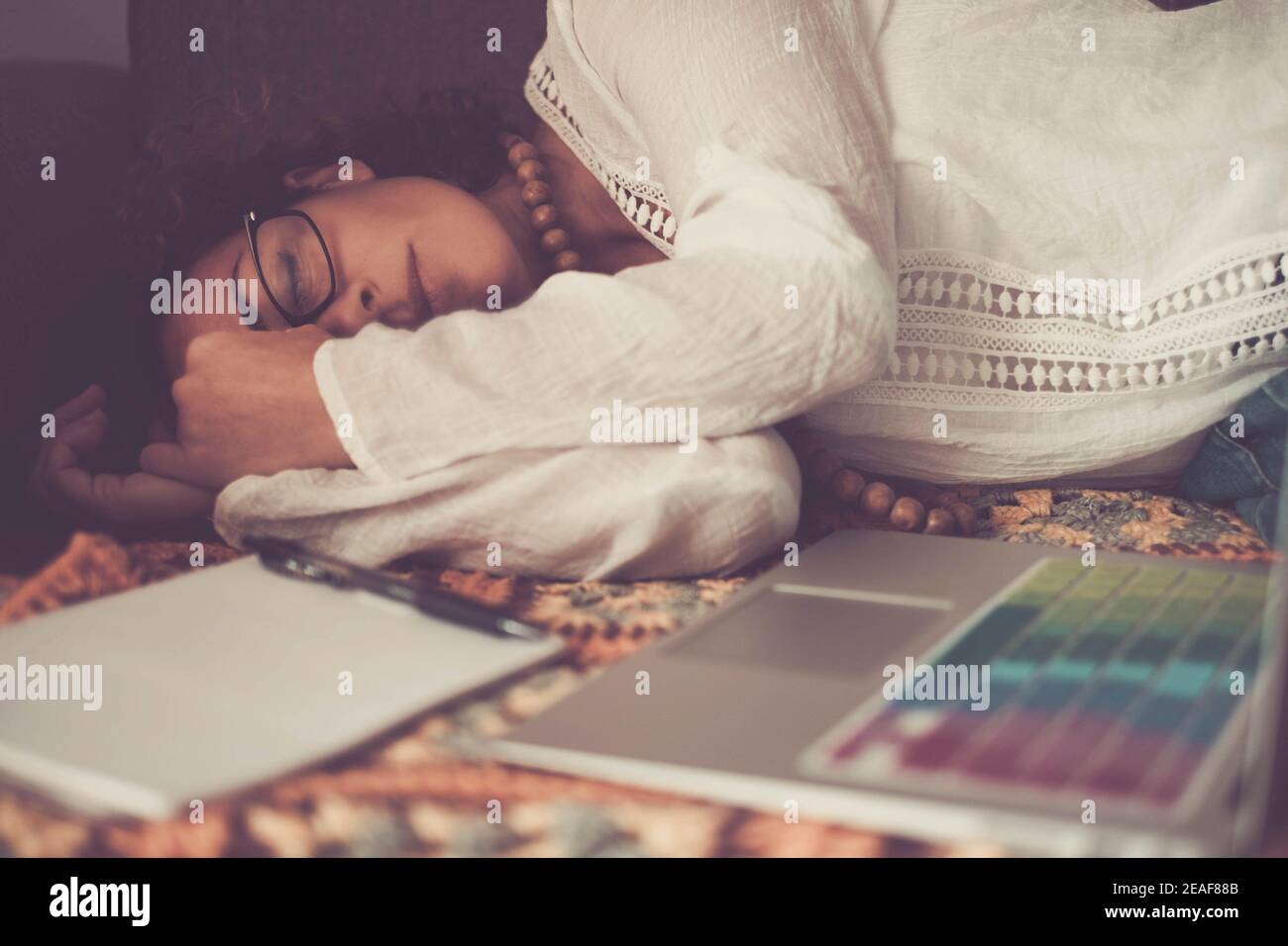 Donna a casa che dorme sul divano dopo troppo duro lavoro in linea con il computer portatile - concetto di lavoro intelligente non c'è tempo per riposarsi, ma dopo no c'è gente stanca Foto Stock