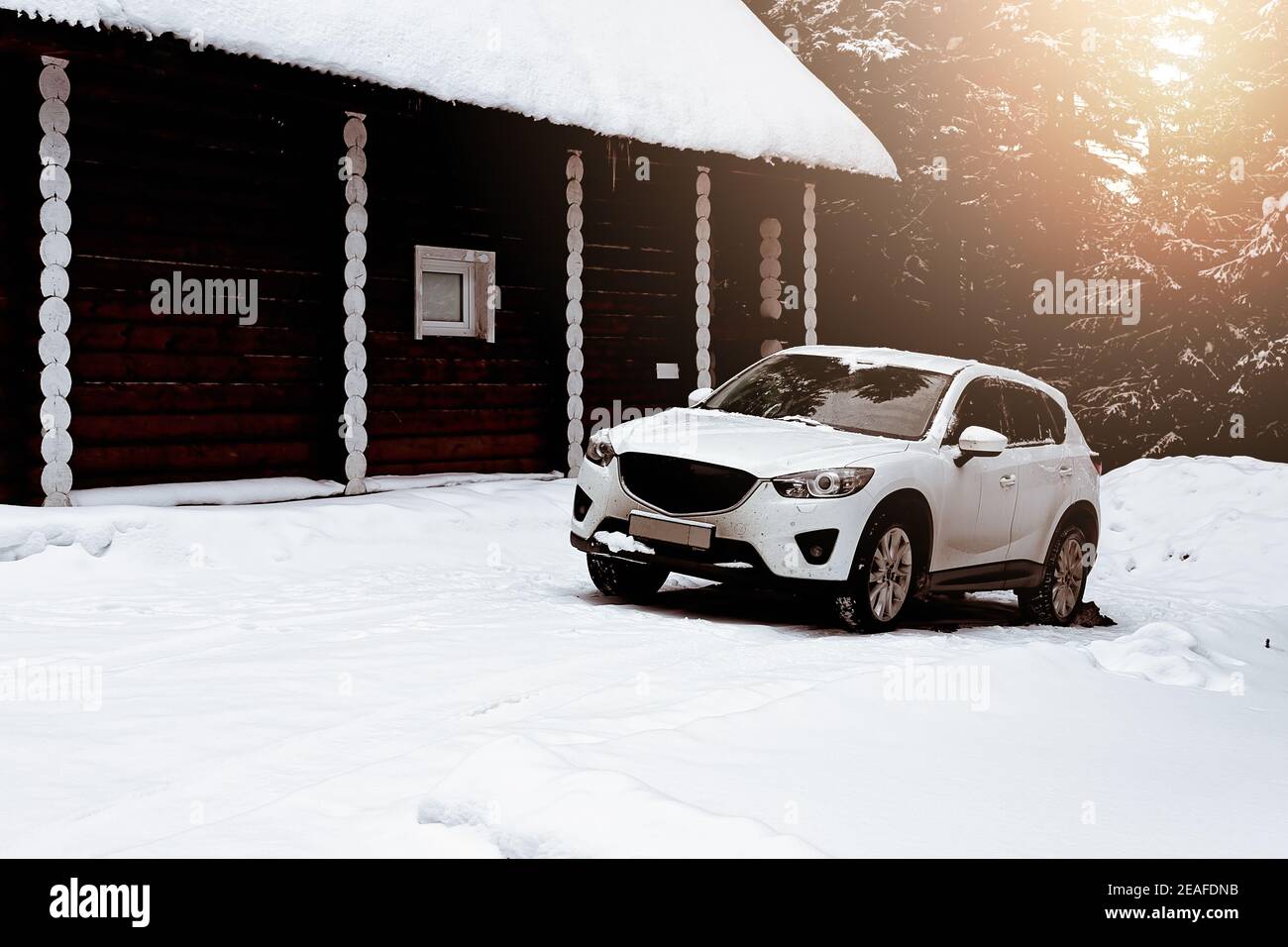 Auto bianca nel parcheggio di fronte ad una casa di legno. Cottage di tronchi. Alloggiamento realizzato in materiali da costruzione naturali. Struttura ecocompatibile. Vita dentro Foto Stock